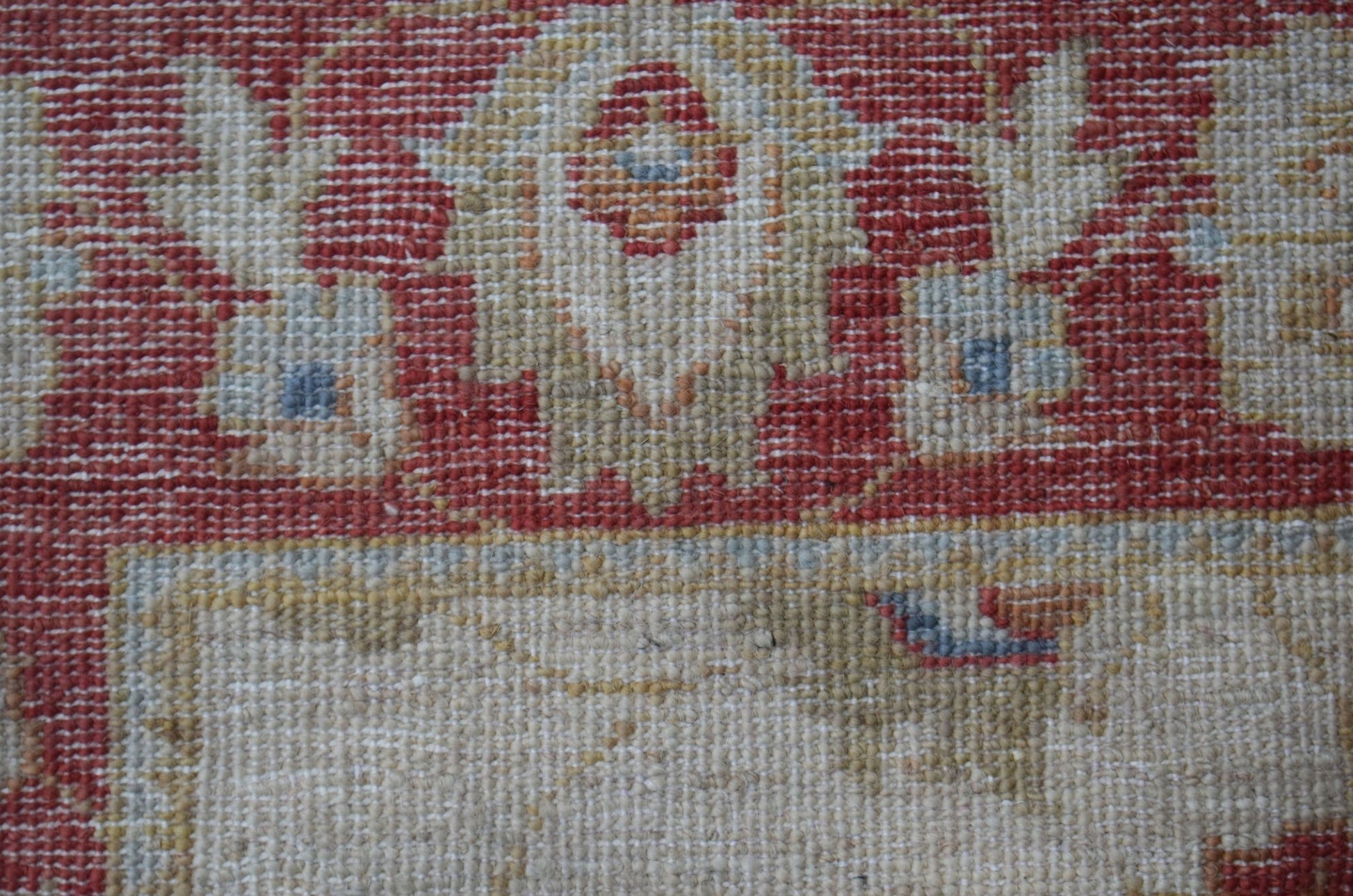 A close-up of a handwoven Afghan Chobi rug featuring traditional floral patterns in red and beige.