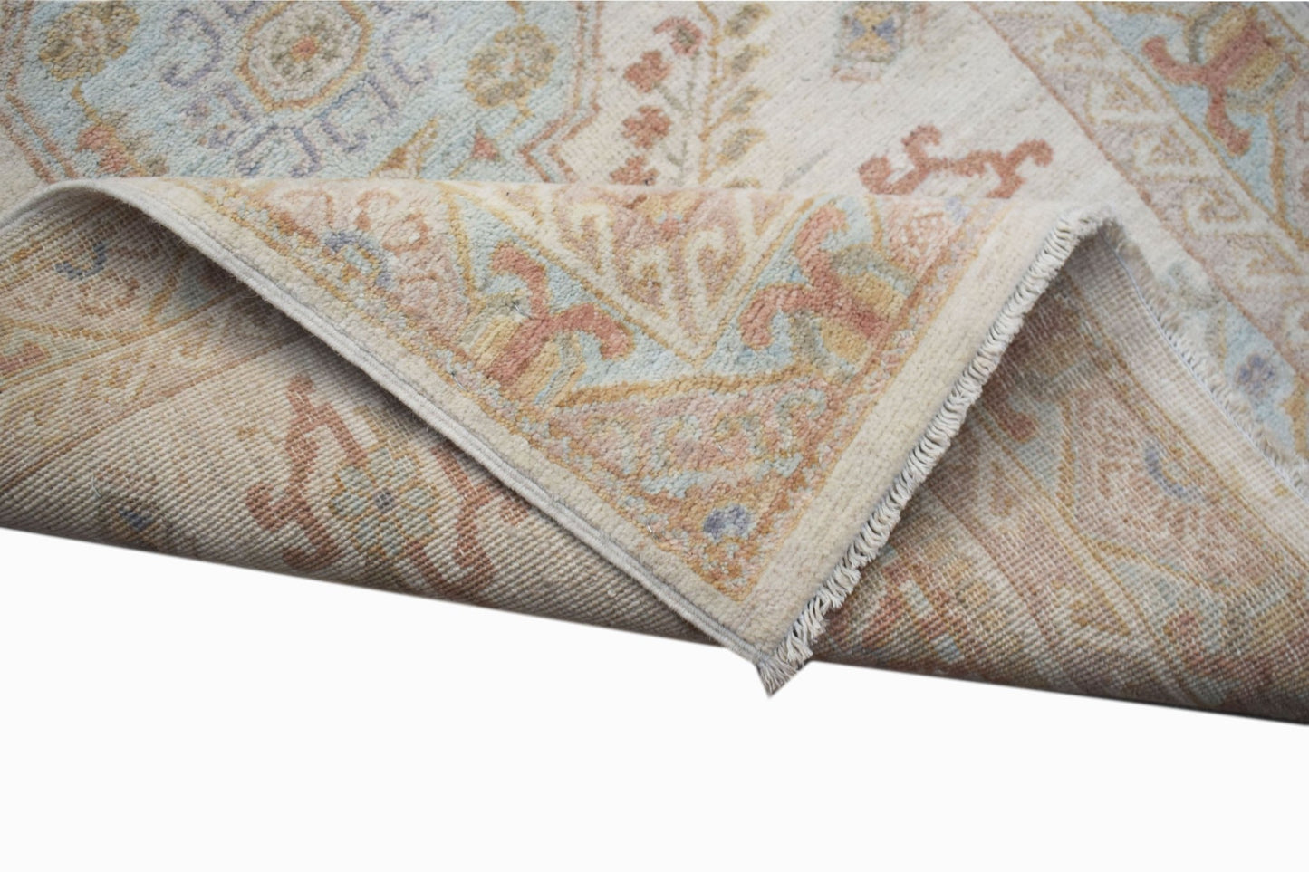 A corner of a handwoven Afghan Chobi rug featuring traditional floral patterns in soft earth tones.