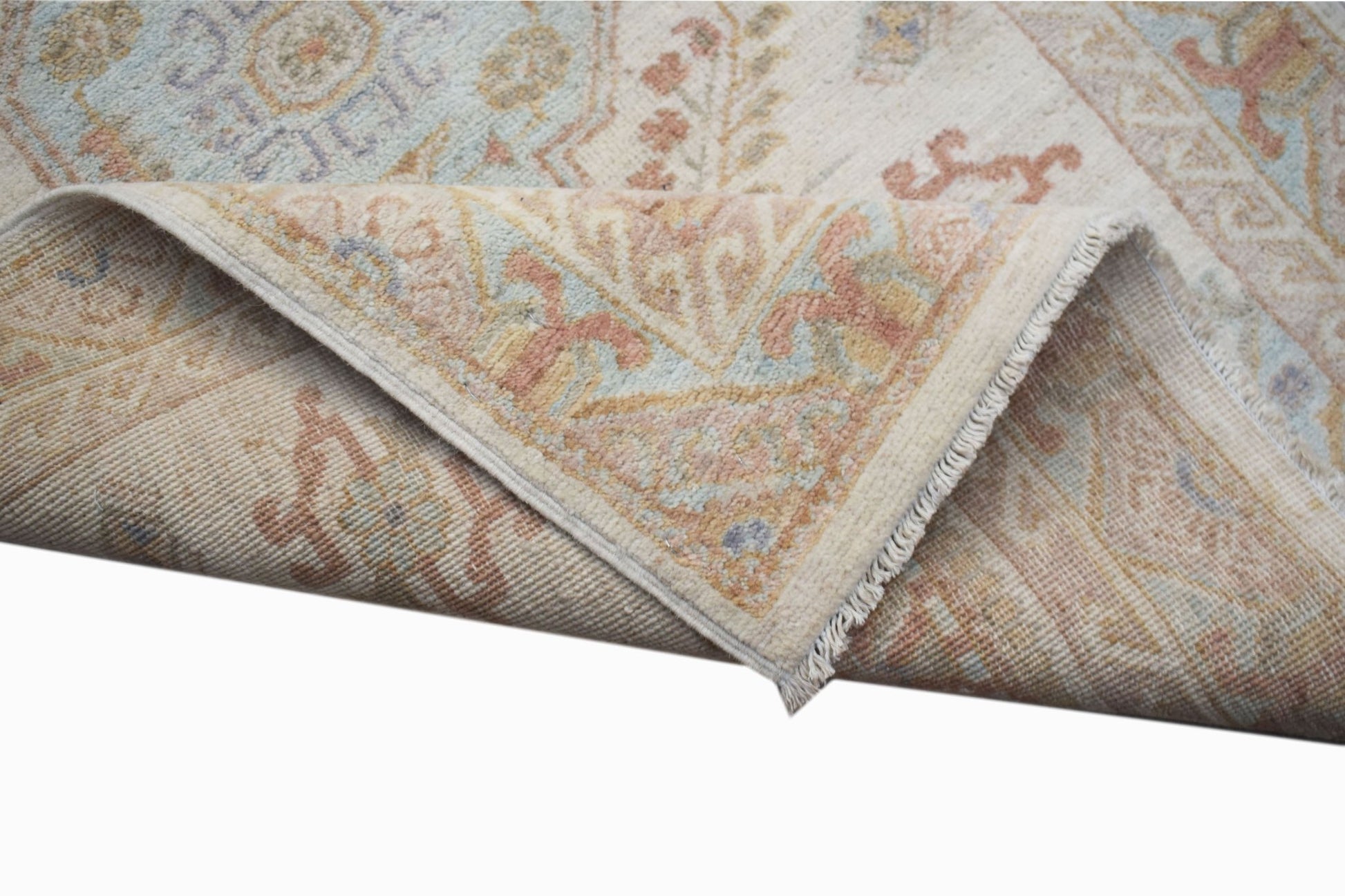 A corner of a handwoven Afghan Chobi rug featuring traditional floral patterns in soft earth tones.