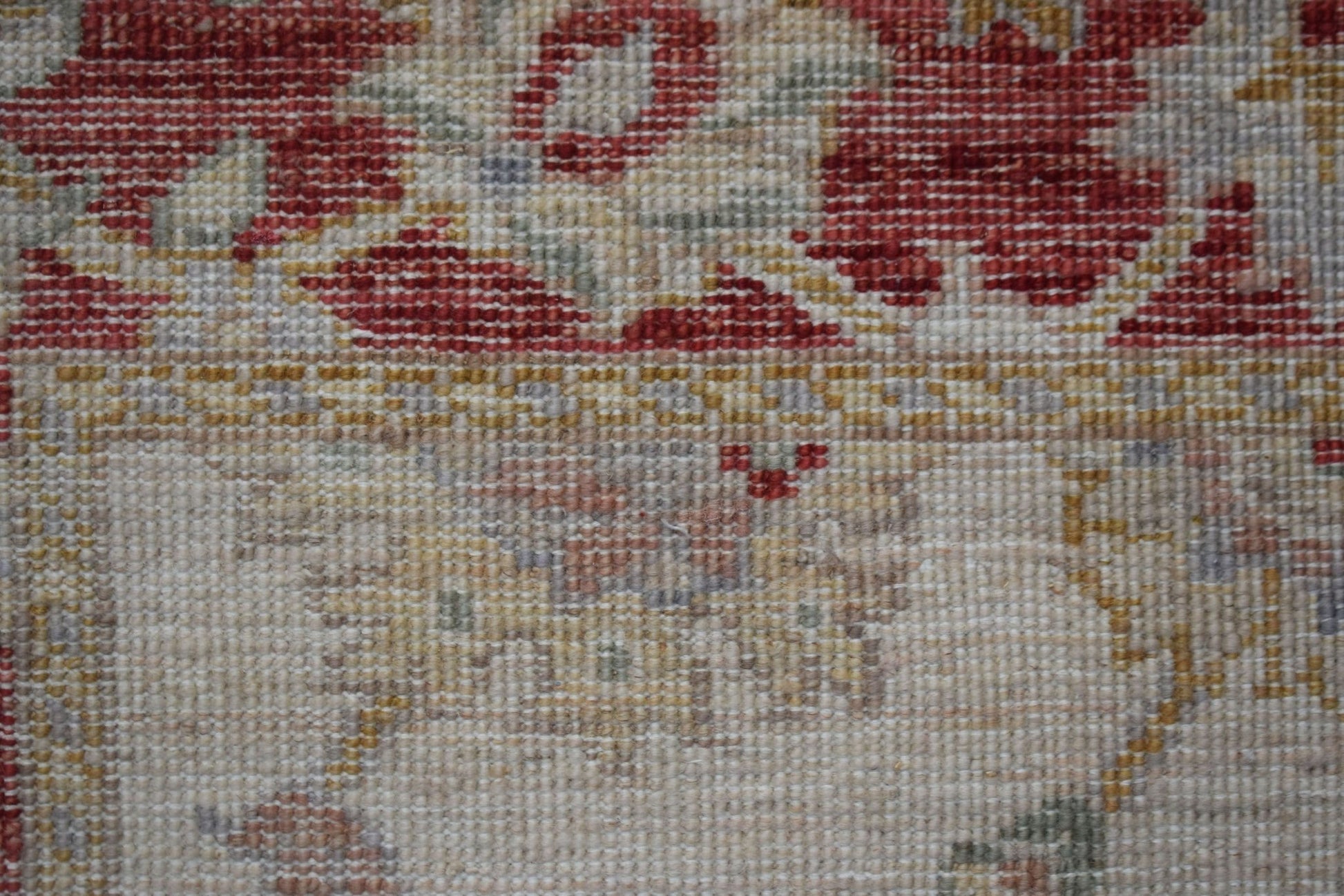 A close-up of a handwoven Afghan Chobi rug featuring traditional floral patterns in red and gold.