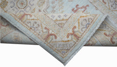 A handwoven Afghan Chobi rug featuring a traditional floral pattern in soft blue and beige tones.