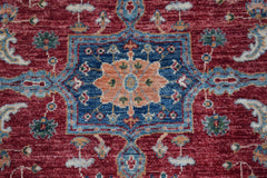 A handmade Afghan Chobi rug featuring a central floral medallion on a deep red background.