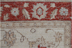 A close-up of a handmade Afghan Chobi rug featuring a red floral border and a beige field.