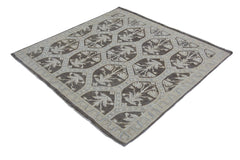 A square Afghan Chobi rug featuring a repeating floral pattern in brown and cream tones.