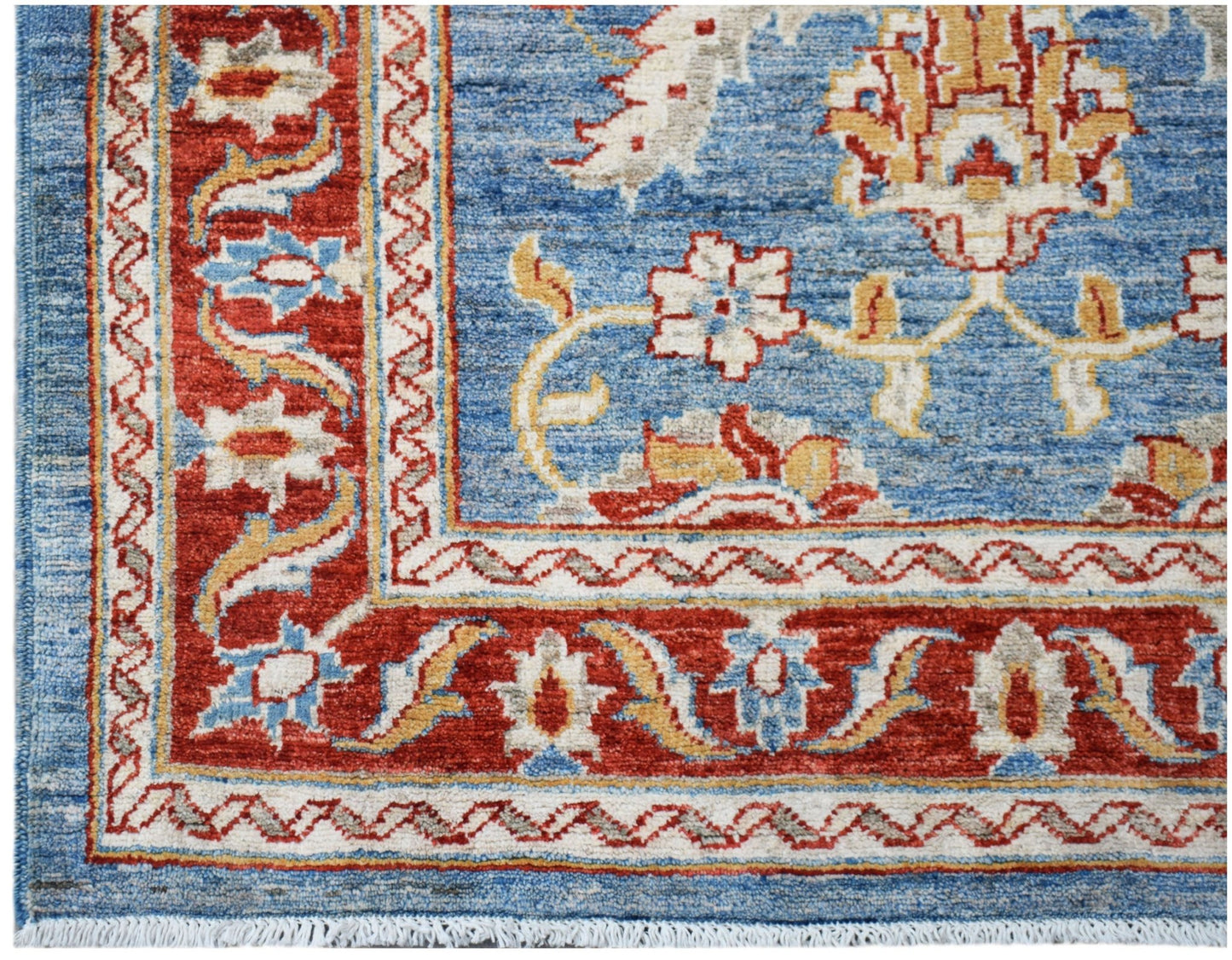 A handwoven Afghan Chobi rug featuring a blue field with floral motifs and a red border.