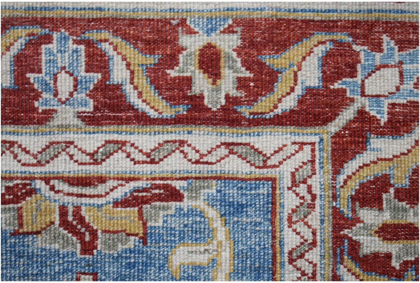 A close-up of an Afghan Chobi rug featuring intricate floral patterns in red, blue, and cream.