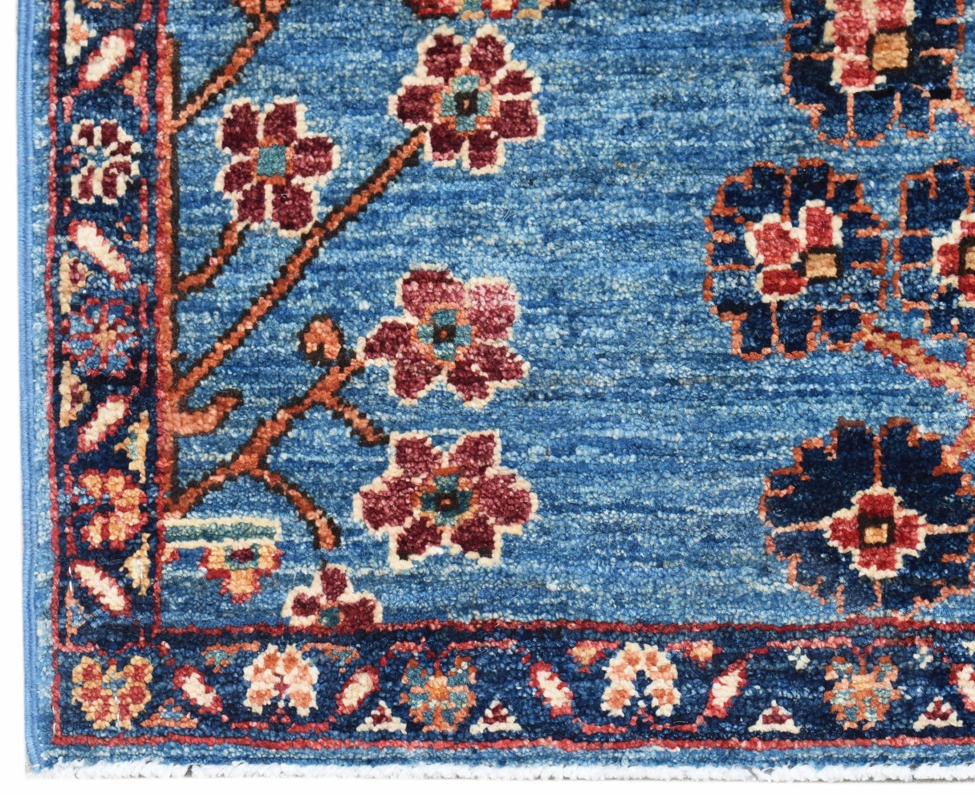 A handwoven Afghan Chobi rug featuring a blue field with floral patterns and a decorative border.