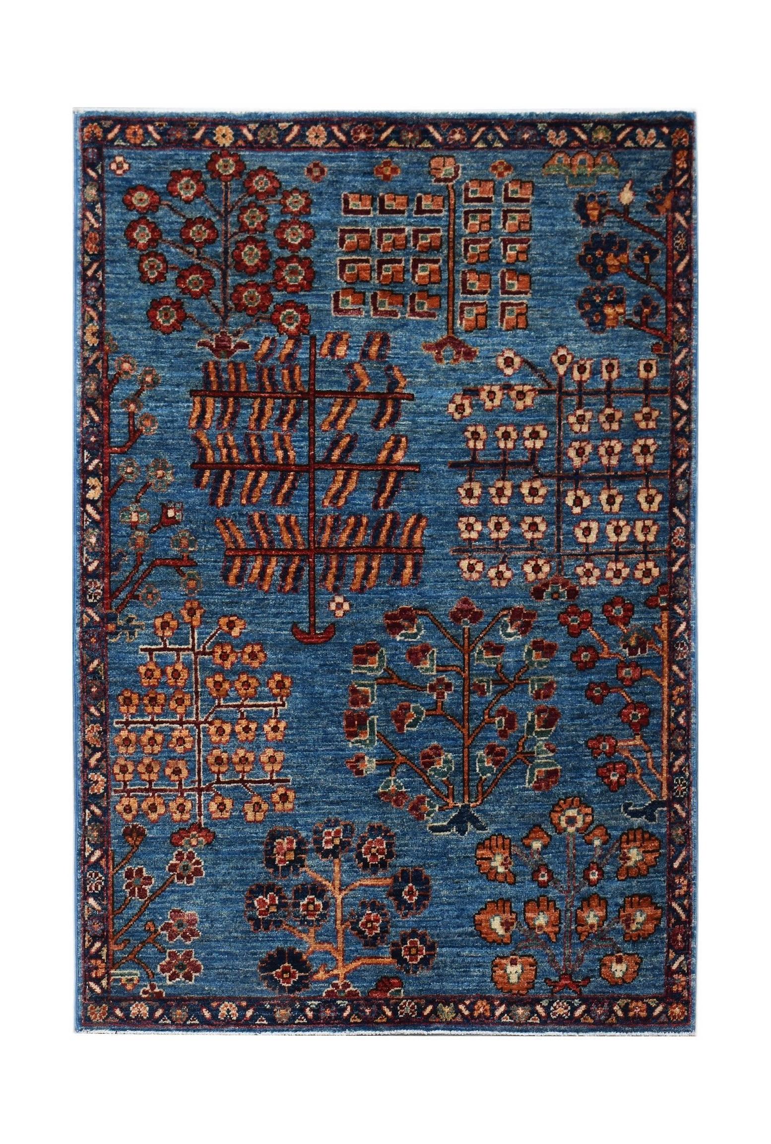 A rectangular Afghan Chobi rug featuring a blue field with stylized tree and floral motifs.