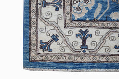 A corner view of a handwoven Afghan Chobi rug featuring blue and cream floral patterns.