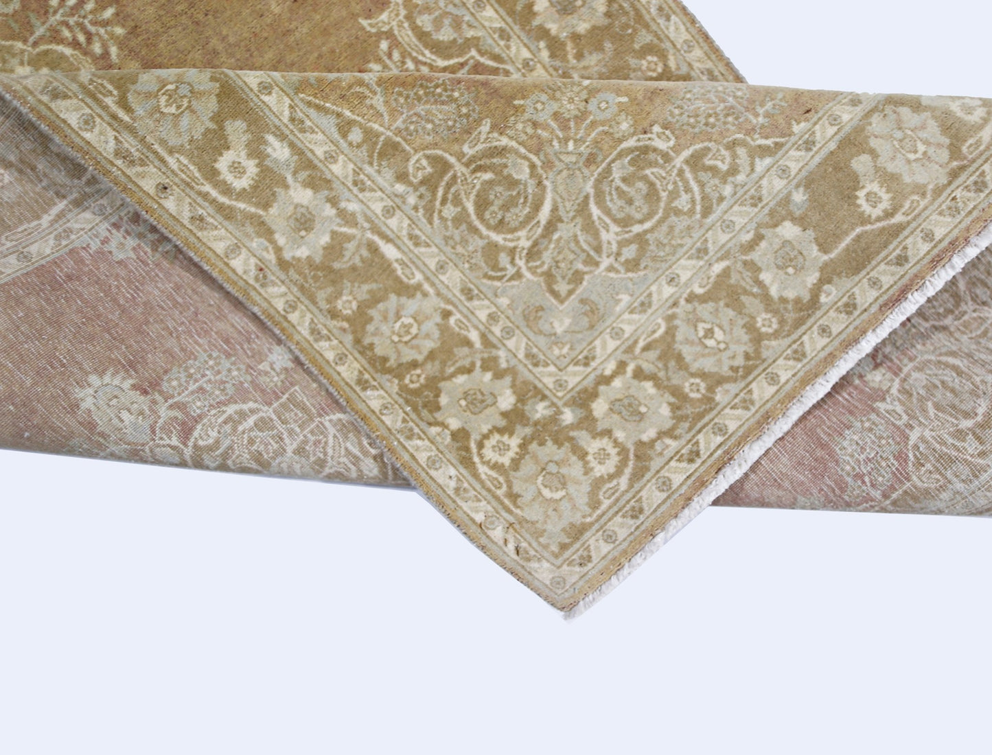 A folded Afghan Chobi rug featuring a traditional floral pattern in muted beige and dusty rose tones.