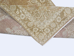 A folded Afghan Chobi rug featuring a traditional floral pattern in muted beige and dusty rose tones.