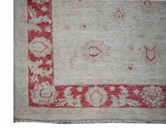 A handmade Afghan Chobi rug featuring a red floral border on a light beige wool field.