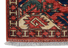 A close-up of an Afghan Chobi rug featuring a red field with geometric patterns and white fringe.