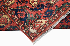 A folded Afghan Chobi rug featuring traditional geometric patterns in red, blue, and cream wool.