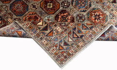 A handwoven Afghan Chobi rug featuring geometric patterns in earthy tones on a grey background.