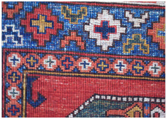 A close-up of a handmade Afghan Chobi rug featuring intricate geometric patterns in red and blue.
