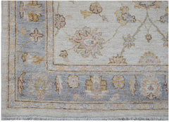 A handmade Afghan Chobi rug featuring a floral pattern in soft blue and cream tones.
