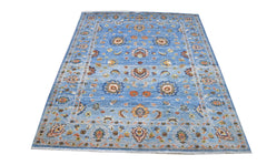A rectangular Afghan Chobi rug featuring intricate floral patterns in earthy tones on a blue field.