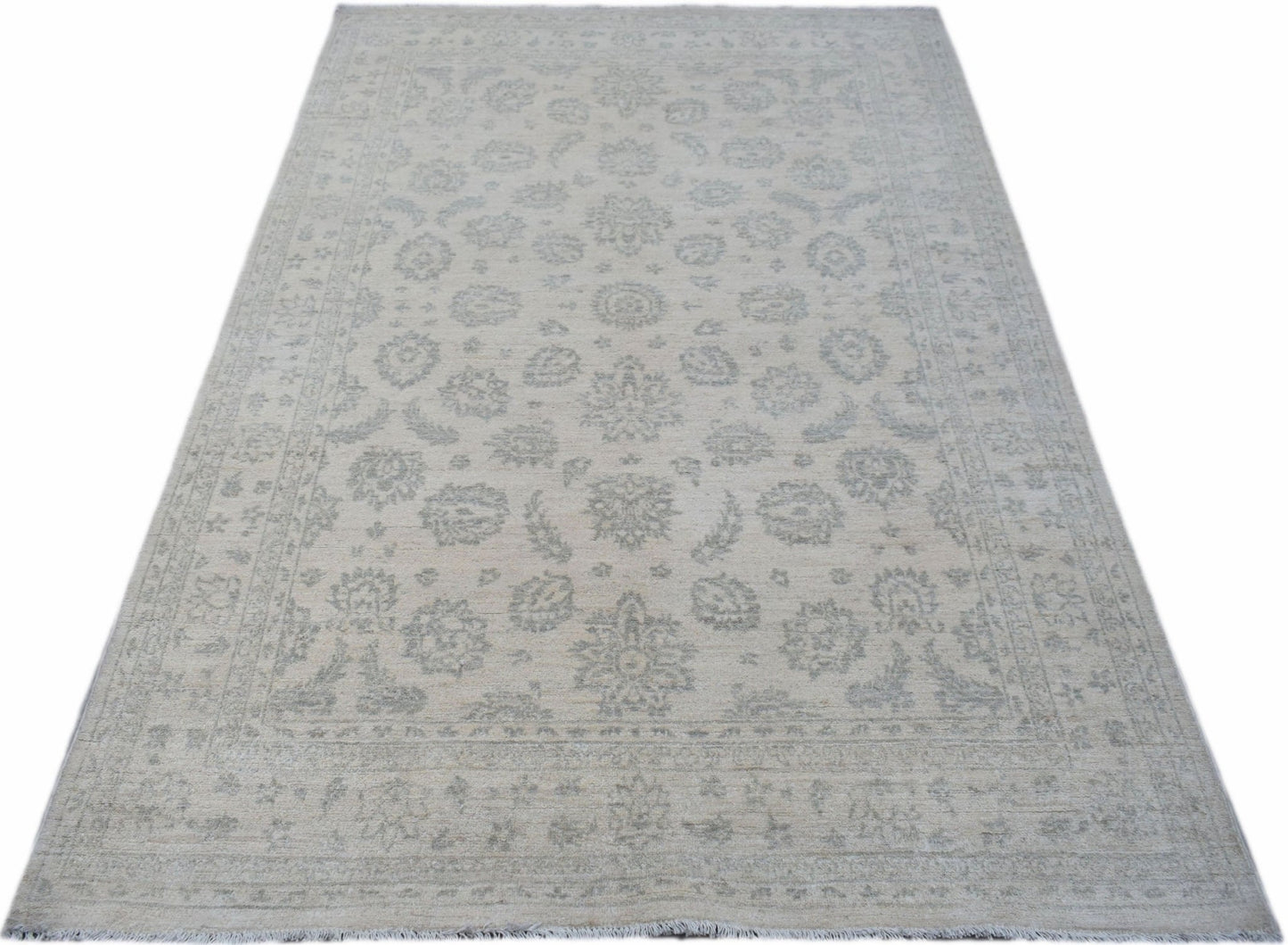 A handmade Afghan Chobi rug featuring a traditional floral pattern in soft grey and beige tones.