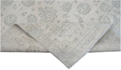 A handwoven Afghan Chobi rug featuring a traditional floral pattern in soft beige and grey tones.