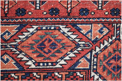A close-up of a handwoven Afghan Chobi rug featuring geometric patterns in red, blue, and cream.