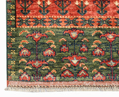 A handwoven Afghan Chobi rug featuring a floral pattern in red, green, and blue on a wool pile.