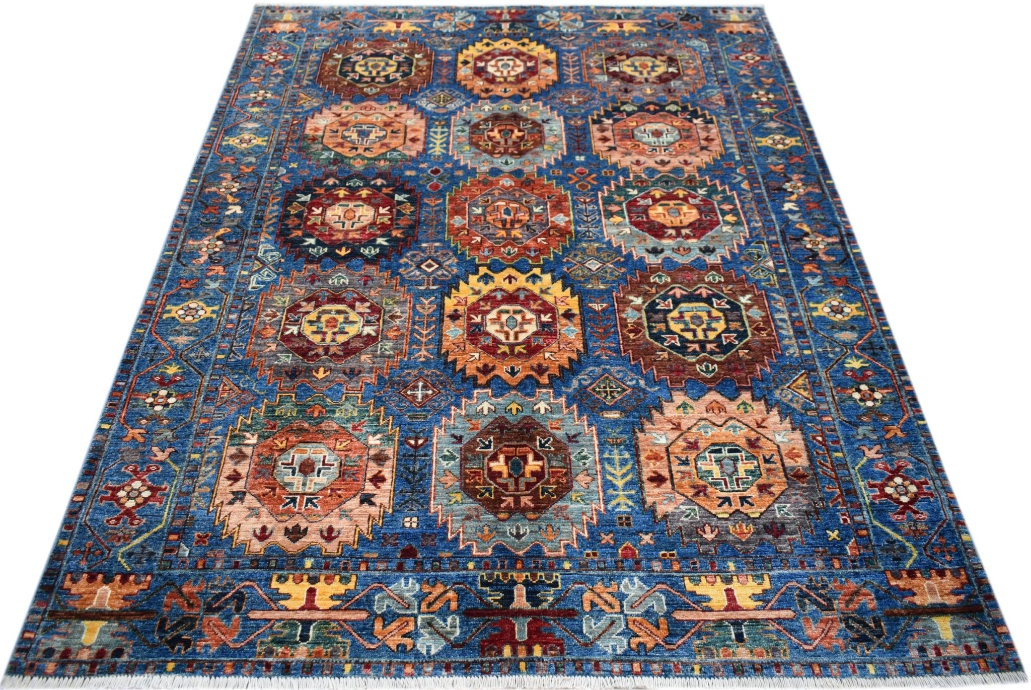 A handmade Afghan Chobi rug featuring a blue field with repeating geometric medallion patterns.