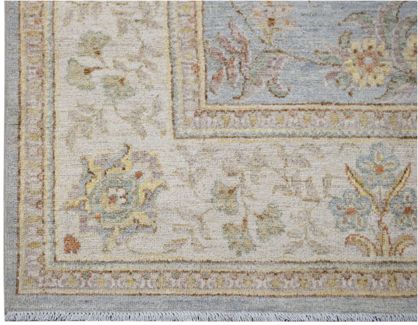 A handwoven Afghan Chobi rug featuring a floral pattern in soft blue, cream, and earthy tones.