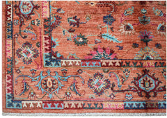 A handmade Afghan Chobi rug featuring intricate floral patterns in shades of orange, blue, and pink.