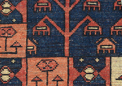 A close-up of a handwoven Afghan Chobi rug featuring geometric tree and floral motifs in wool.
