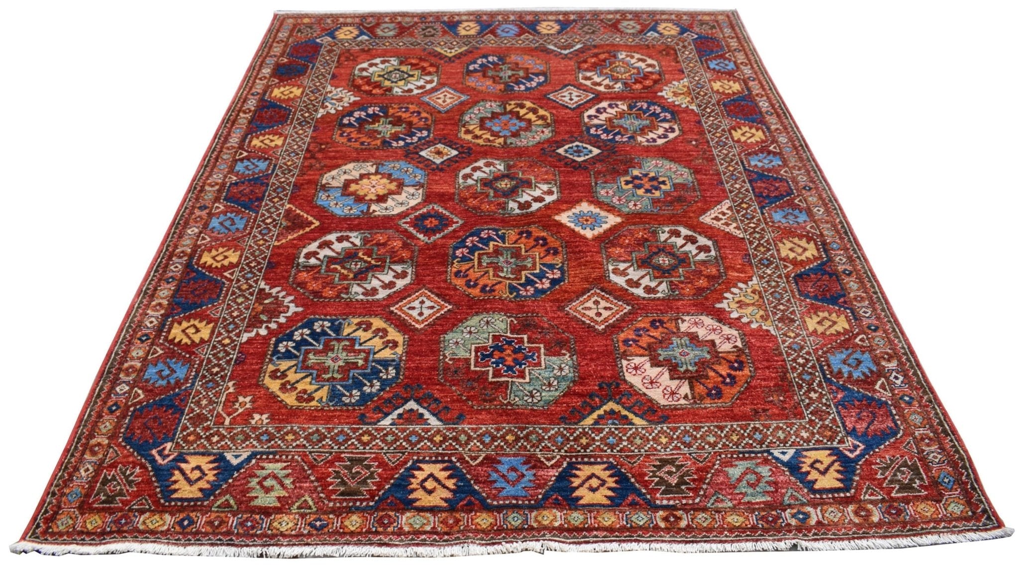 A handmade Afghan Chobi rug featuring a red field with repeating geometric octagonal motifs.