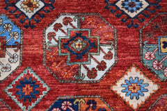 A handmade Afghan Chobi rug featuring a geometric pattern of octagons in red, blue, and cream.