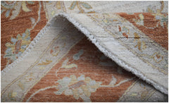 A folded Afghan Chobi rug featuring traditional floral patterns in earthy orange and cream tones.