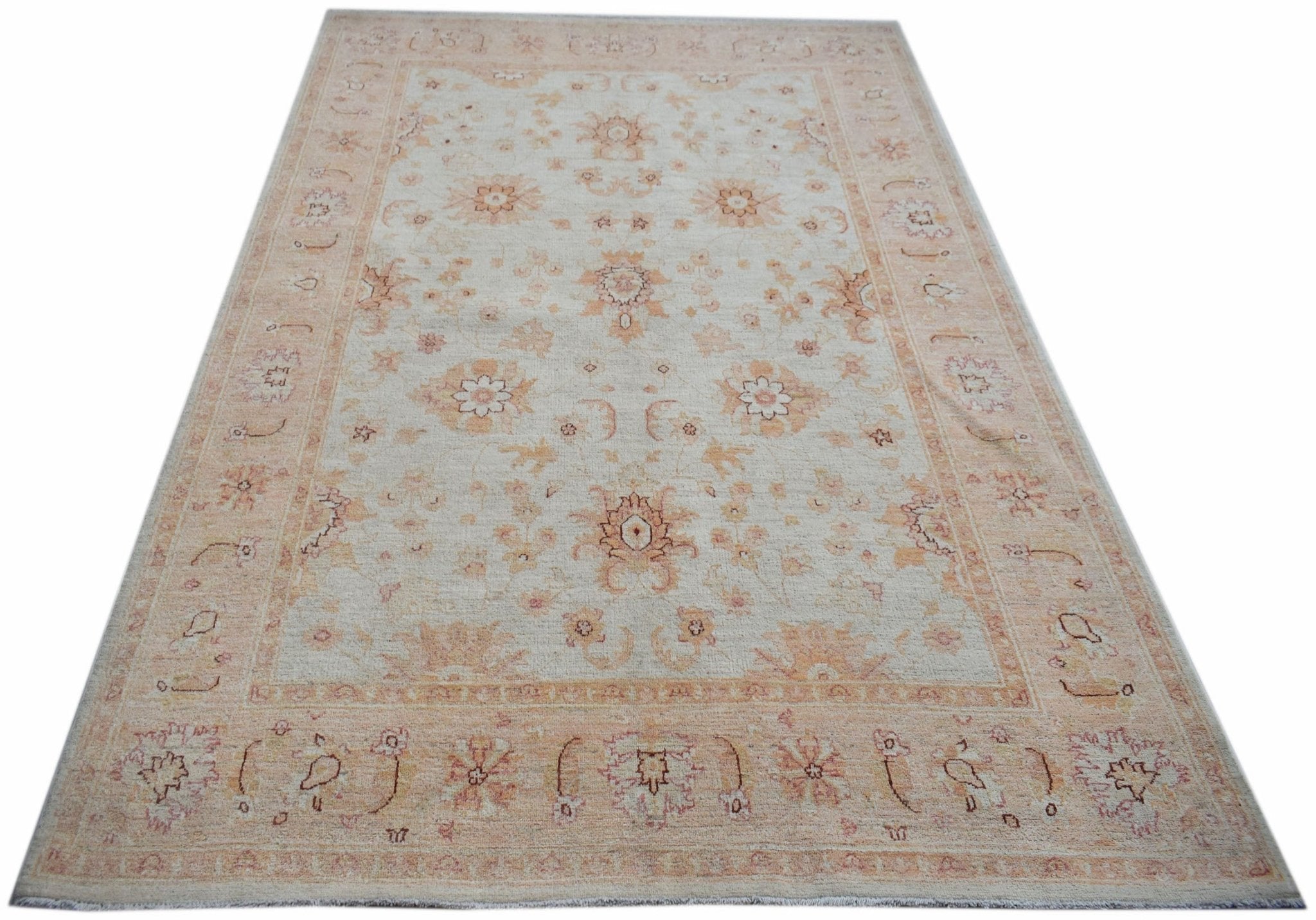 An Afghan Chobi rug featuring a traditional floral pattern in soft beige and peach tones.