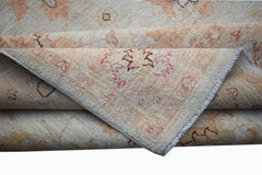 A folded Afghan Chobi rug featuring traditional floral patterns in soft beige and muted pink tones.
