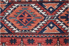 A close-up of an Afghan Chobi rug featuring a geometric diamond pattern in red, blue, and cream.