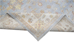A handwoven Afghan Chobi rug featuring a light blue field with floral patterns and a folded corner.