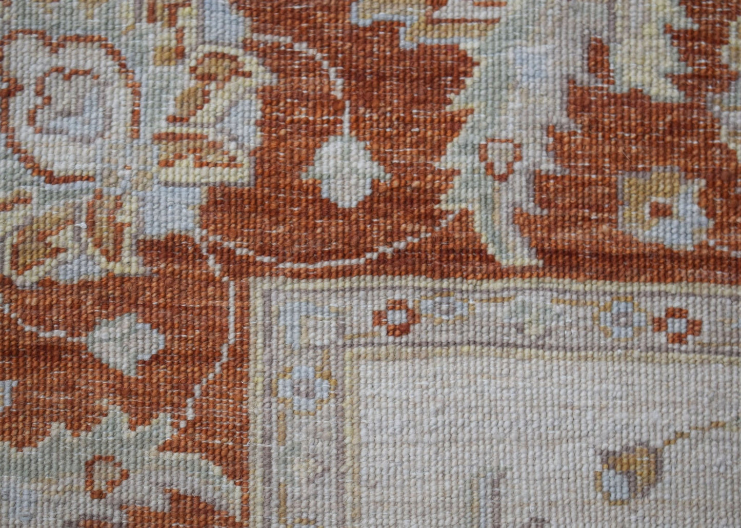 A close-up of a handwoven Afghan Chobi rug featuring intricate floral patterns in rust and cream.