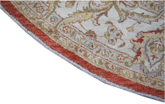 A round Afghan Chobi rug featuring intricate floral patterns in earthy tones with a red border.