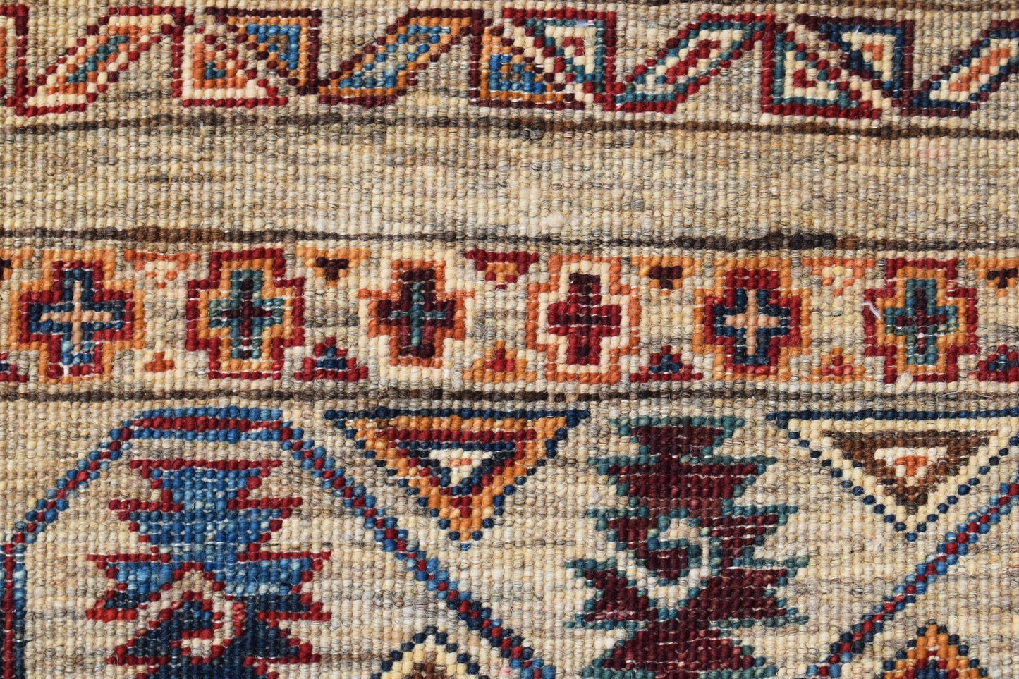 A close-up of a handwoven Afghan Chobi rug featuring geometric patterns in earthy tones.