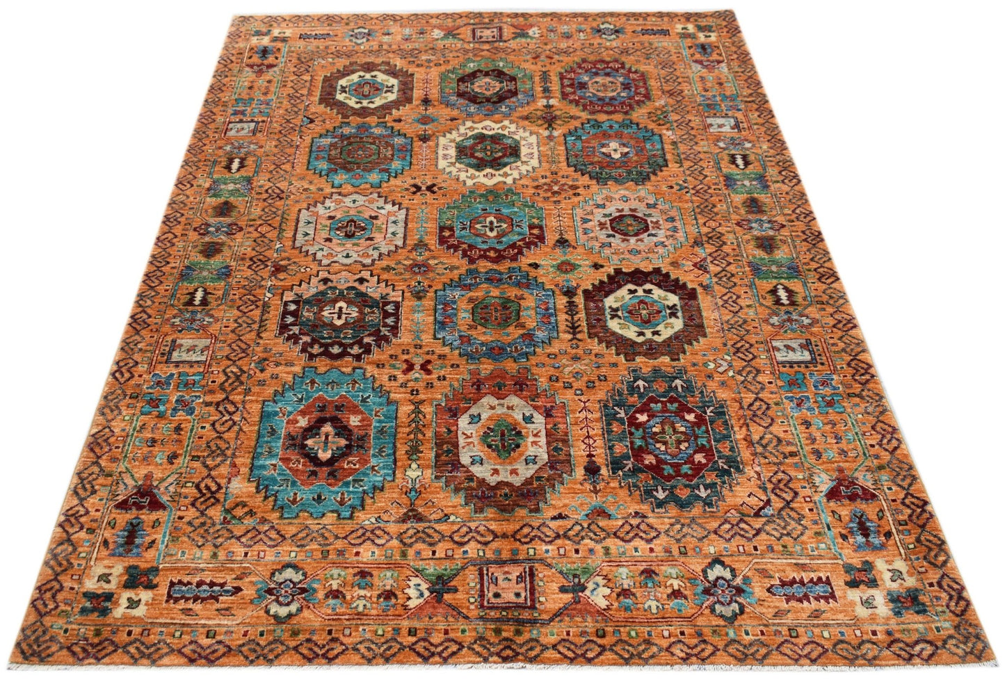 Handwoven Afghan Chobi rug featuring a traditional geometric pattern in warm orange and blue tones.