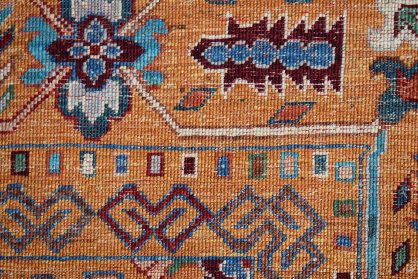 A close-up of a handwoven Afghan Chobi rug featuring intricate floral patterns in warm earth tones.