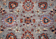 A handwoven Afghan Chobi rug featuring a traditional floral pattern in orange, blue, and cream.