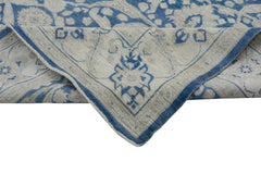 A handmade Afghan Chobi rug featuring a blue and cream floral pattern with a folded corner.