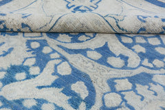 A handmade Afghan Chobi rug featuring a blue and cream floral pattern with a folded corner.