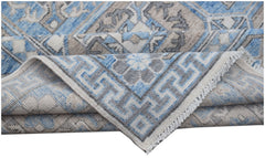 A handmade Afghan Chobi rug featuring a blue, grey, and beige geometric pattern with fringe.