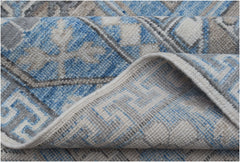 A close-up of a handmade Afghan Chobi rug featuring a blue, grey, and cream geometric pattern.