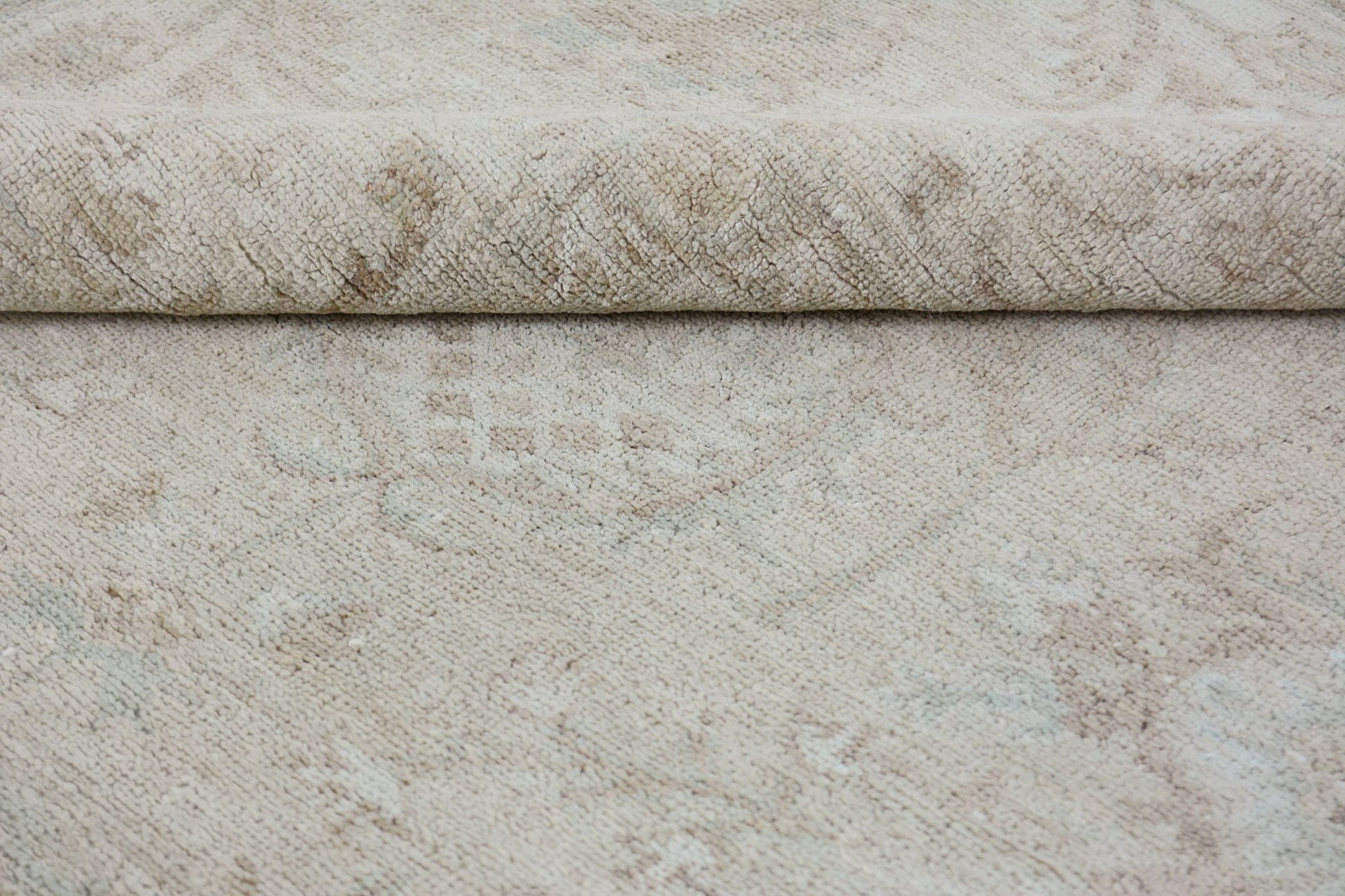 A close-up of a handmade Afghan Chobi rug featuring a neutral beige pattern on a wool pile.