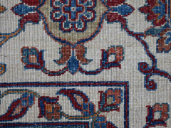 A close-up of an Afghan Chobi rug featuring intricate floral patterns in red, blue, and tan wool.