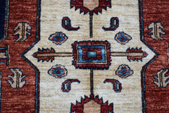 A handwoven Afghan Chobi rug featuring a central geometric medallion on a cream field.